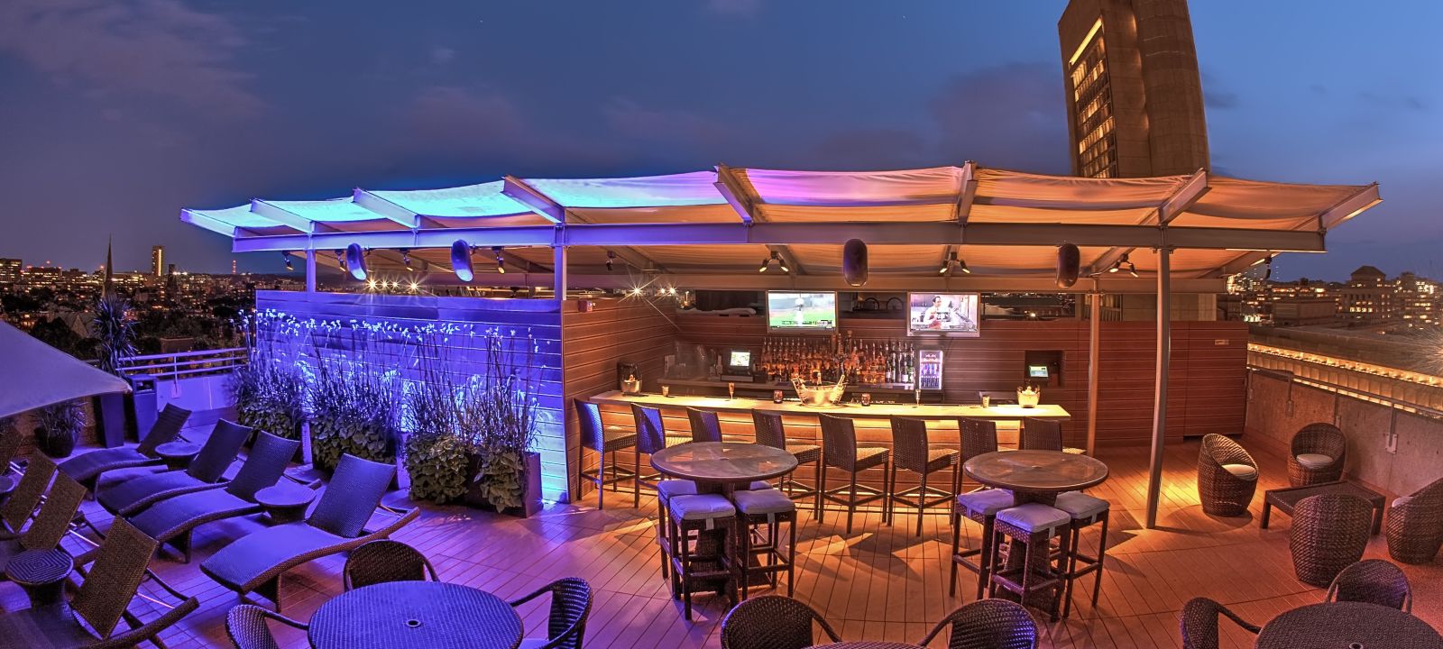 The Colonnade hotel with rooftop bar in Boston along with tables and chairs at night