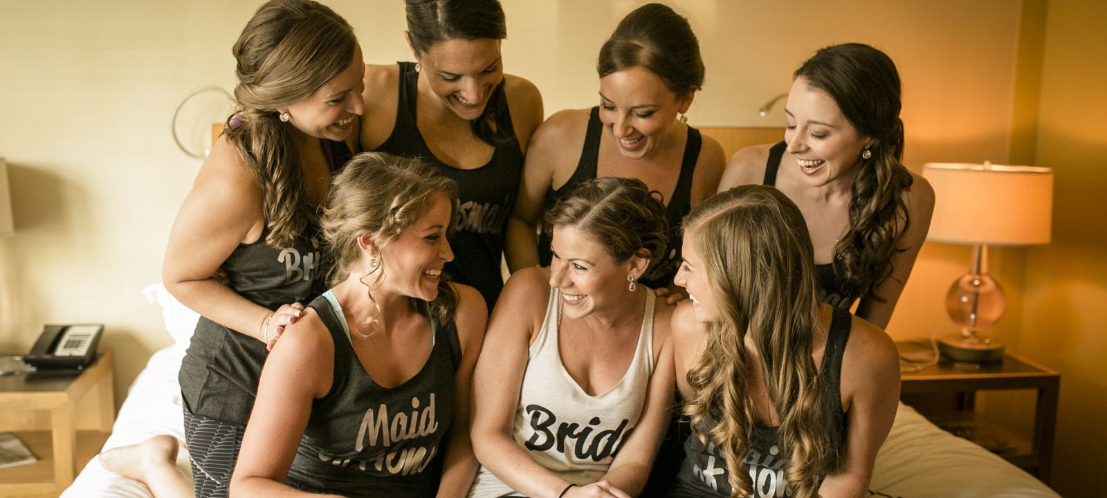 Bridesmaids and a bride smiling at each other at one of Colonnade Hotel's guest suites in Boston